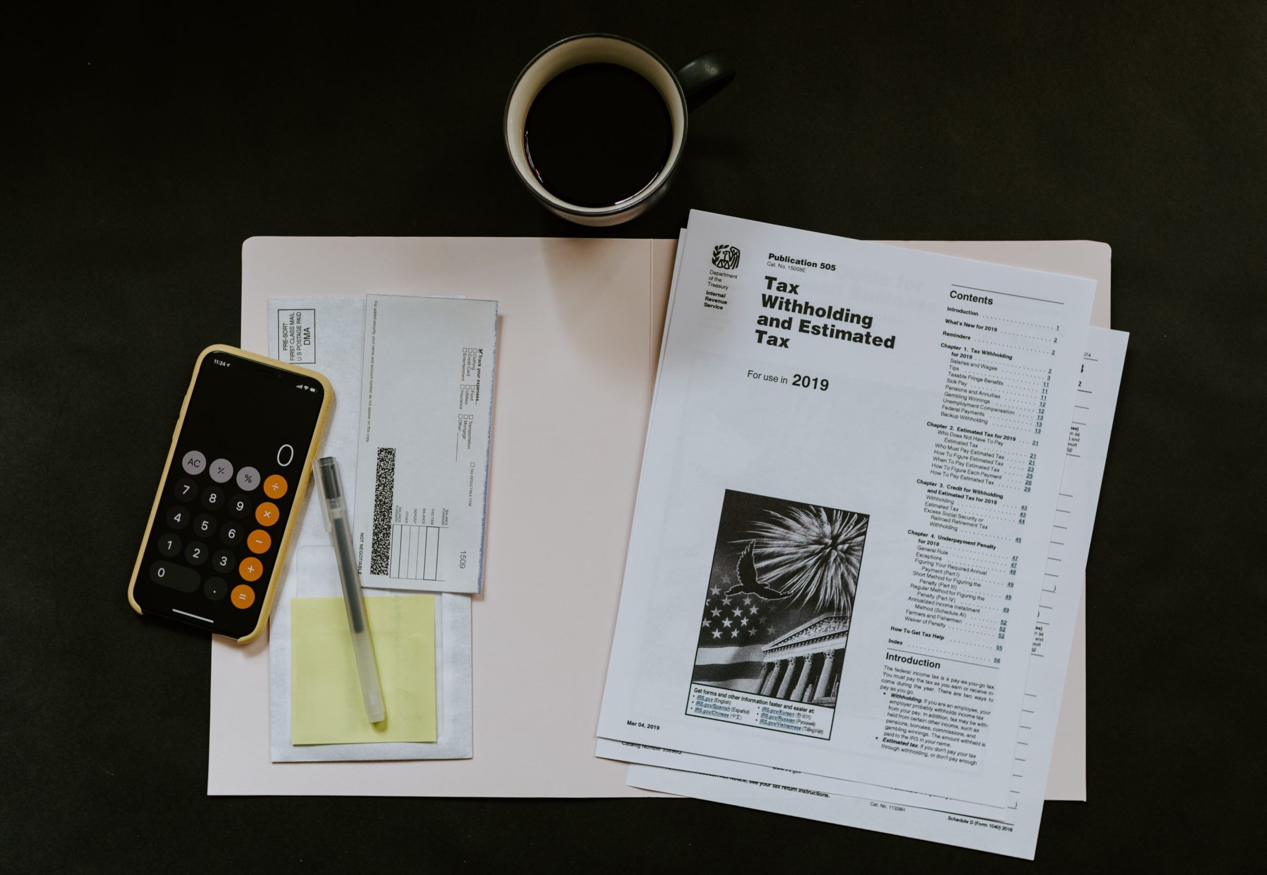Coffee, tax withholding papers, and a calculator